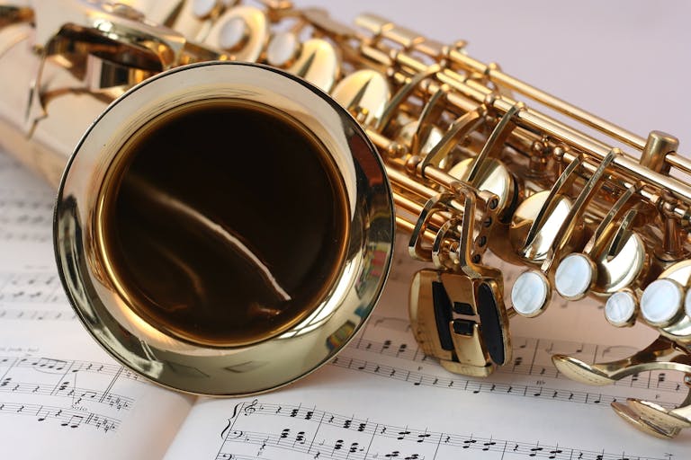 A detailed view of a saxophone resting on sheet music, highlighting its brass finish.